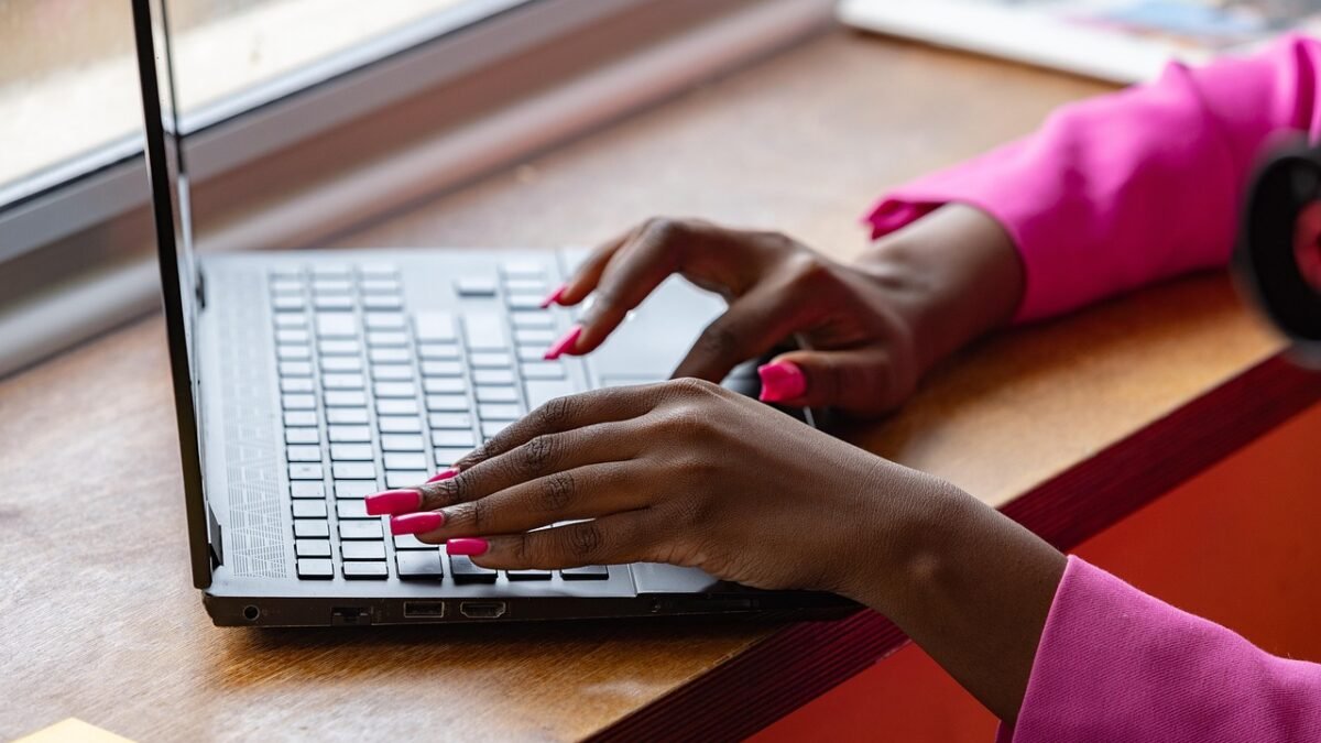 Hands typing on a black Windows laptop keyboard